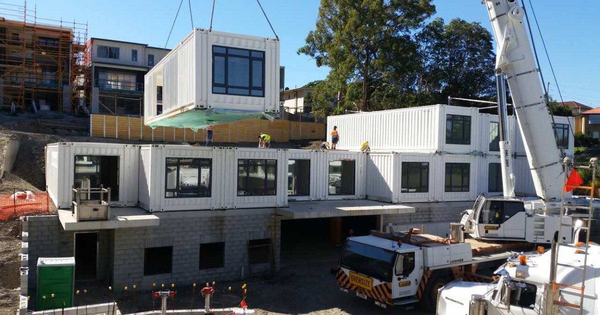 White EcoPrestige modular units craned onto a multi level residential building, the building class where NCC Part E fire safety systems apply